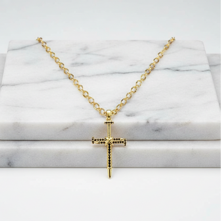 Gold cross necklace on a marble surface