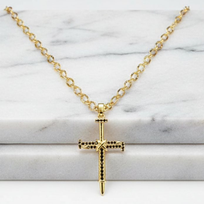 Gold cross necklace on a marble surface