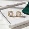Gold earrings with clear gemstones on a white surface