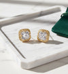 Gold earrings with clear gemstones on a white surface