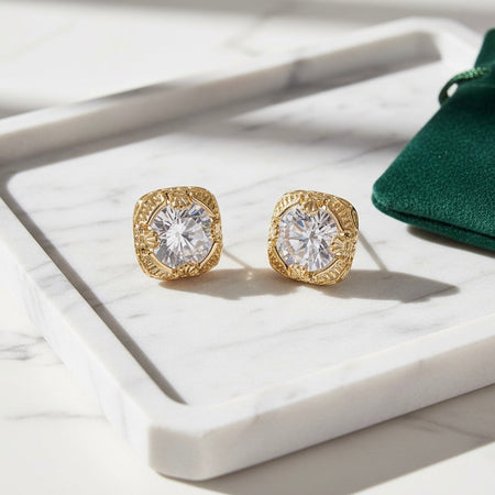 Gold earrings with clear gemstones on a white surface