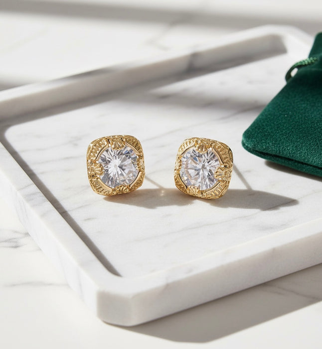 Gold earrings with clear gemstones on a white surface