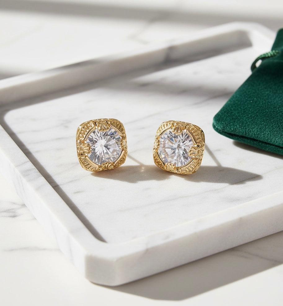 Gold earrings with clear gemstones on a white surface