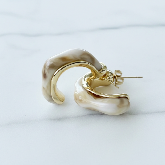 Gold and beige hoop earring on a light gray background