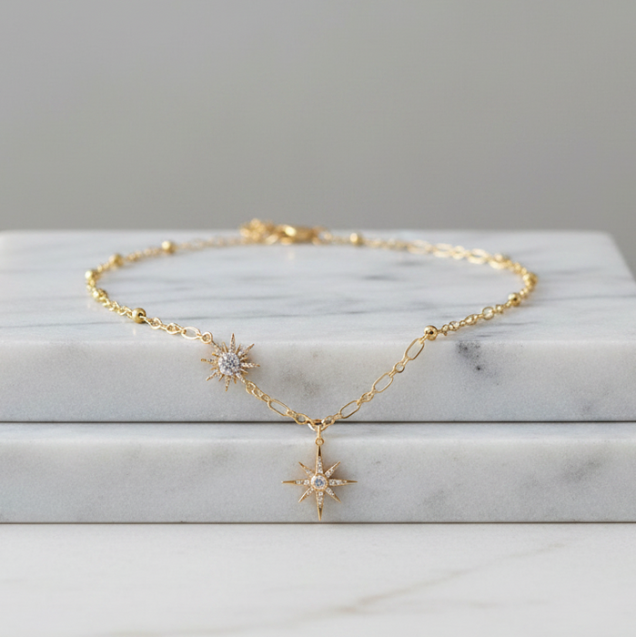 Gold necklace with star-shaped pendants on a marble surface