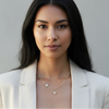 Woman wearing a white blazer over a sheer top with a gray background