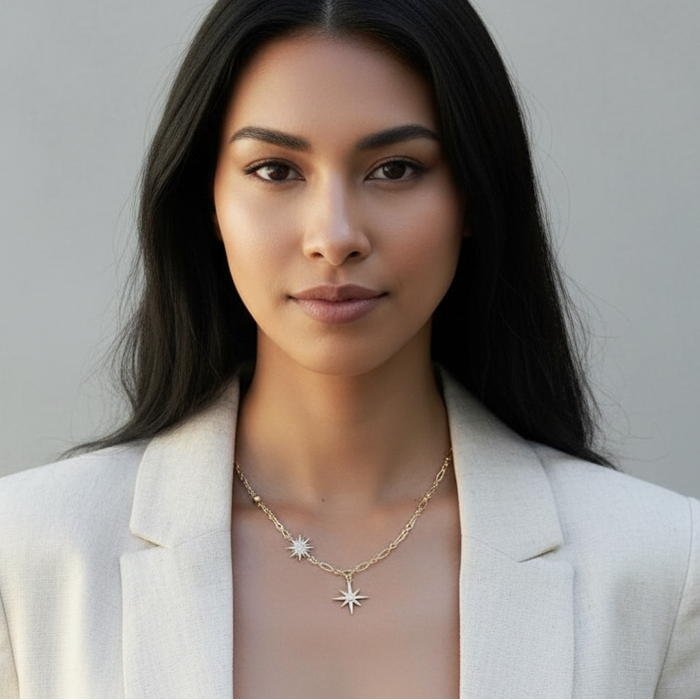 Woman wearing a white blazer over a sheer top with a gray background