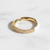 Gold open ring with embedded stones on a light background