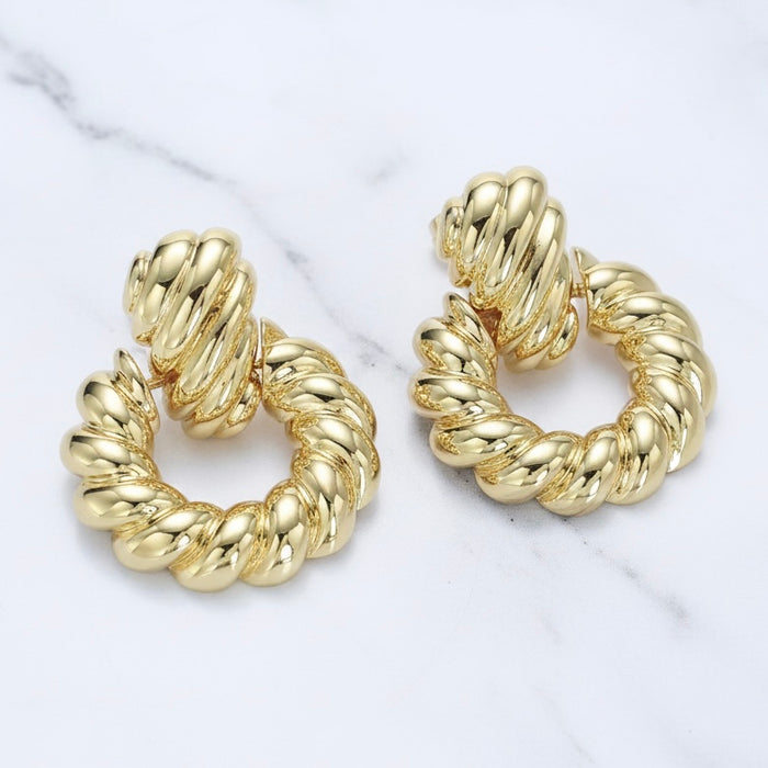 Gold hoop earrings on a marble surface
