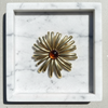 Gold brooch with a central gemstone on a marble surface