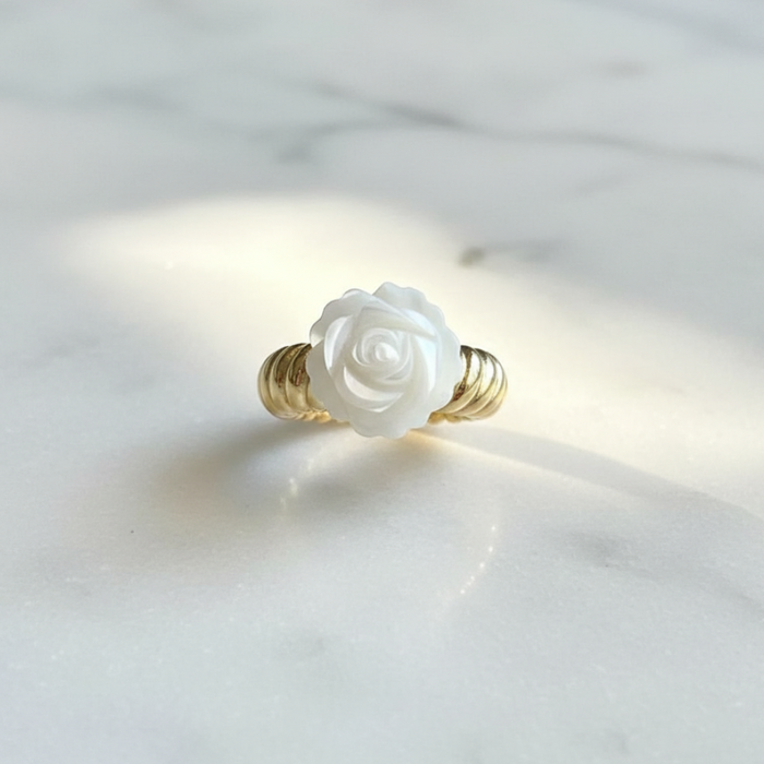 Ring with a white rose design on a light gray background