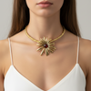 Woman wearing a gold necklace with a red gemstone on a neutral background