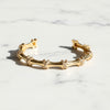 Gold bracelet with intricate design on a marble surface