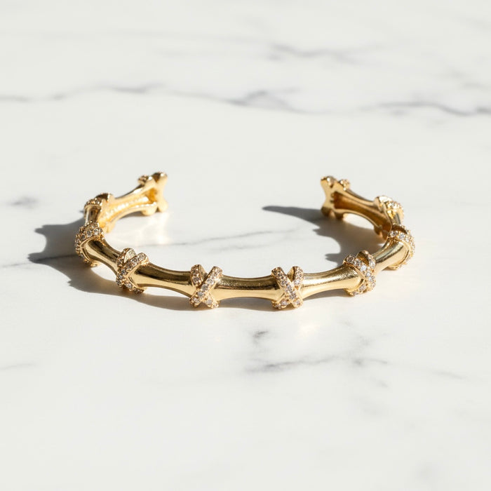 Gold bracelet with intricate design on a marble surface