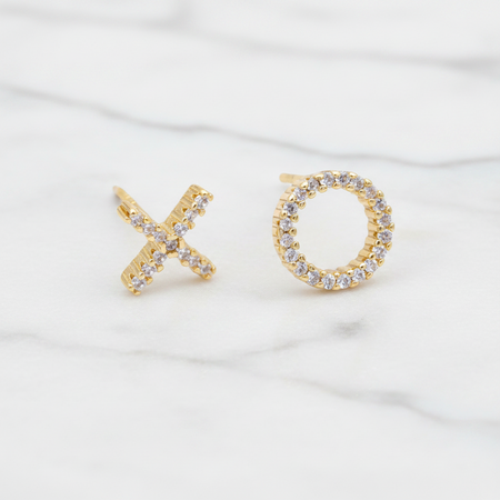 Gold earrings shaped like 'X' and 'O' on a white background
