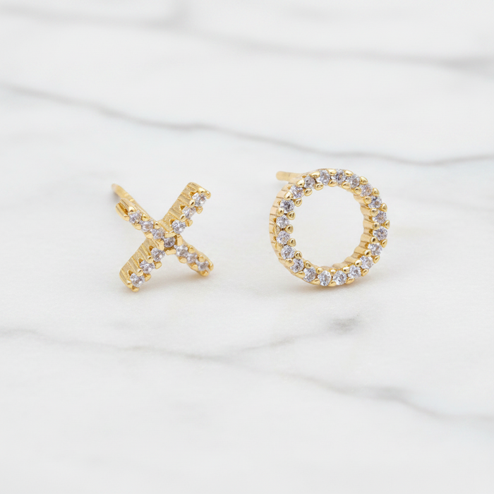Gold earrings shaped like 'X' and 'O' on a white background