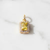 Gold pendant with a yellow gemstone on a white marble background