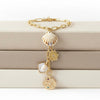 Gold necklace with shell and coin charms on a beige jewelry box