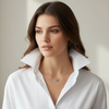 Woman wearing a white shirt and a necklace with a green pendant against a neutral background