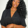 Woman with styled hair wearing a black top against a plain background