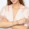Woman wearing gold jewelry including necklaces, bracelets, and rings on a white background