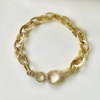 A gold-filled hammered style chain bracelet with a large lobster claw clasp adorned with micro pave diamonds, displayed on a white surface.