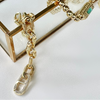 Gold chain bracelet with various links on a white background