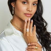 Woman wearing gold jewelry against a plain background