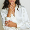 Woman wearing a white shirt with jewelry on a plain background