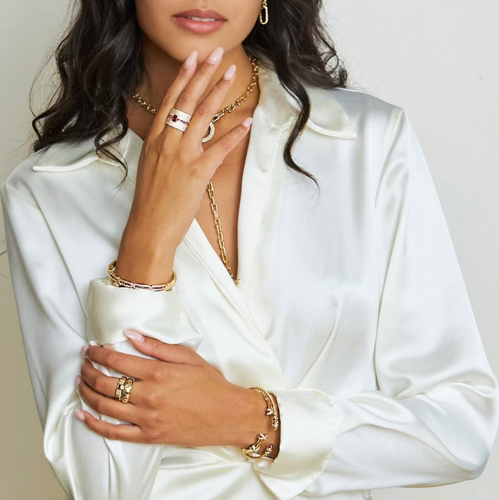 Woman wearing a white shirt with jewelry on a plain background