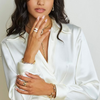 Woman wearing a white satin robe with jewelry on a plain background