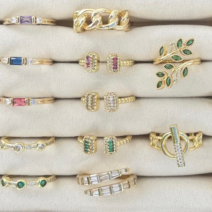 Collection of gold and gemstone rings on a white surface