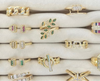Collection of gold rings with various designs and gemstones on a white surface