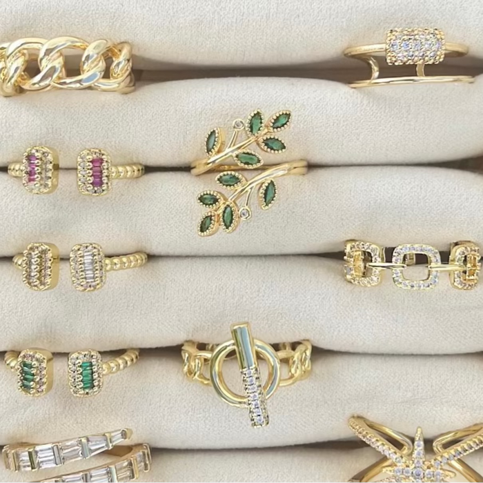 Collection of gold rings with various designs and gemstones on a white surface