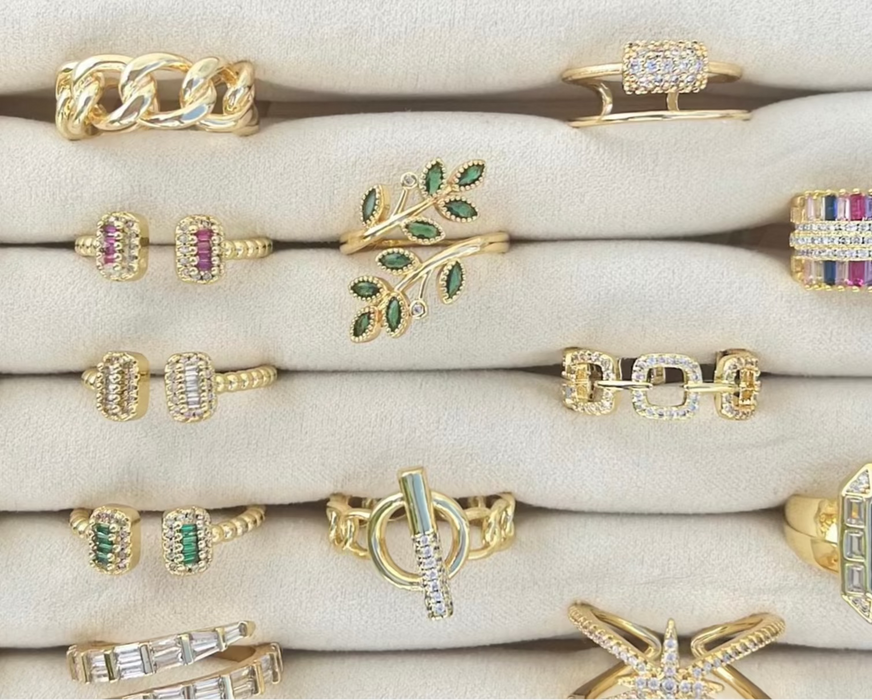 Collection of gold rings with various designs and gemstones on a white surface