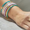 Close-up of a wrist wearing colorful bangles on a neutral background