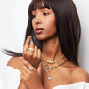 Woman wearing gold jewelry including necklaces, rings, and a bracelet on a white background