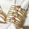 Set of gold bracelets with gemstones on a white fabric background