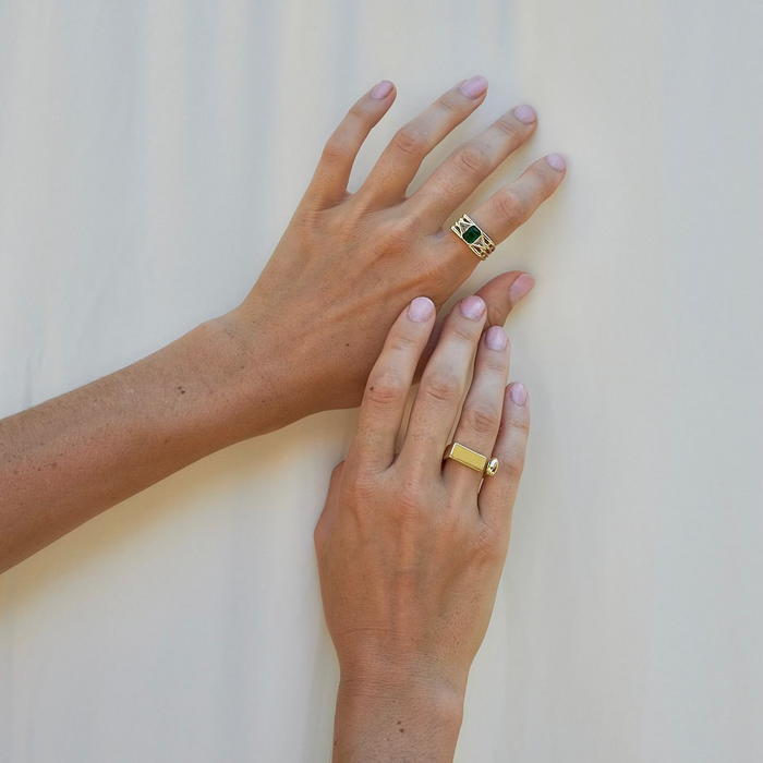 Two hands with gold rings and bracelets on a light background
