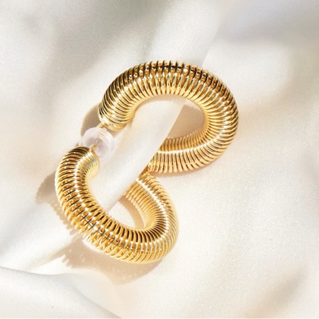 Gold hoop earrings on a white fabric background