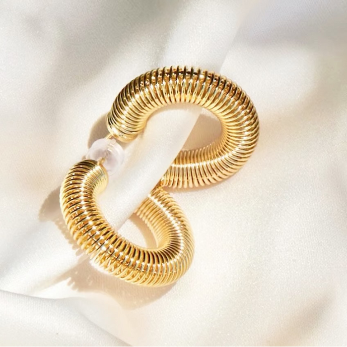 Gold hoop earrings on a white fabric background